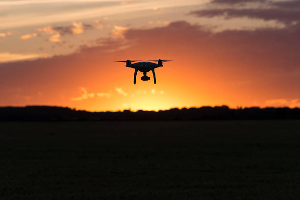 istock Drone silhouetted against orange sunset 584592308