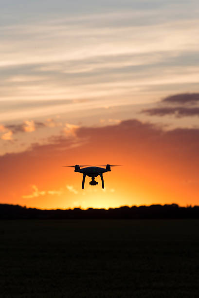 drone silueteado contra la puesta de sol naranja - dron fotos fotografías e imágenes de stock