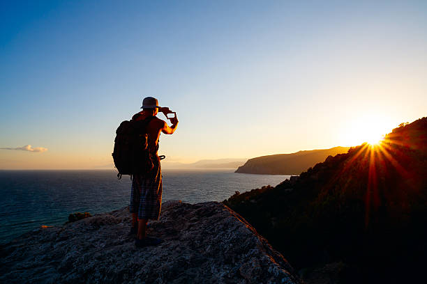 istock landscape photographer man on cliff abovesea summer rays setting sun 584594566