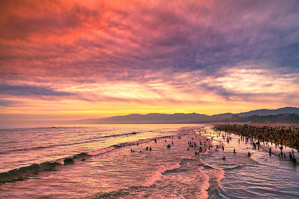 Clouds and haze induced by windswept smoke from a fire in the Angeles National Forest produced a dramatic sunset in Santa Monica. The beach, the silhouettes of swimmers and the Santa Monica Mountains in the background.