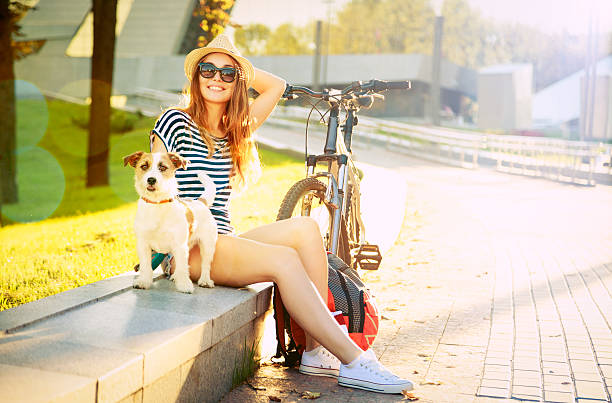 smiling hipster girl avec son chien à summer city - candid people casual bicycle photos et images de collection