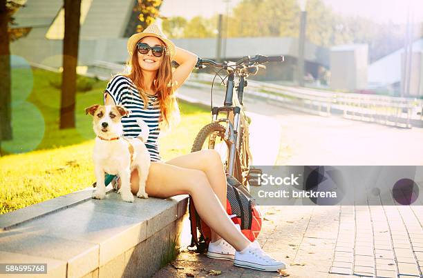 Smiling Hipster Girl With Her Dog In Summer City Stock Photo - Download Image Now - Women, Dog, Bicycle