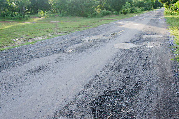 istock Damaged asphalt pavement road with potholes 584596300