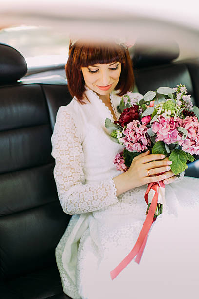 istock Gorgeous bride with beautiful smile is sitting in wedding car 584597010