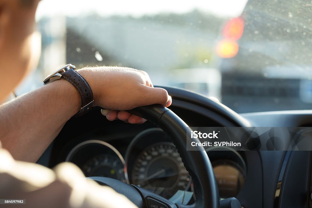 Man behind the wheel in the evening. Man behind the wheel in the evening. Young man goes in the car to home after work. Taxi Driver Stock Photo