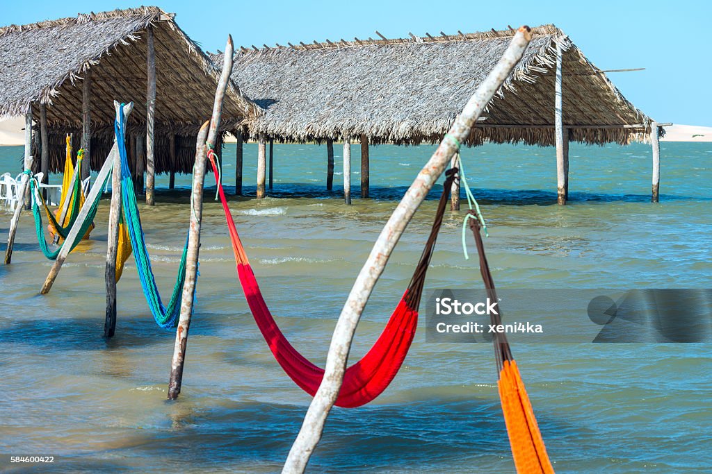 Hammocks under the shade of palapa sunroof in Jericoacoara, Brazil Hammocks and beach chairs under the shade of a palapa sun roof umbrella in Jericoacoara, Brazil Jeriquaquara Beach Stock Photo