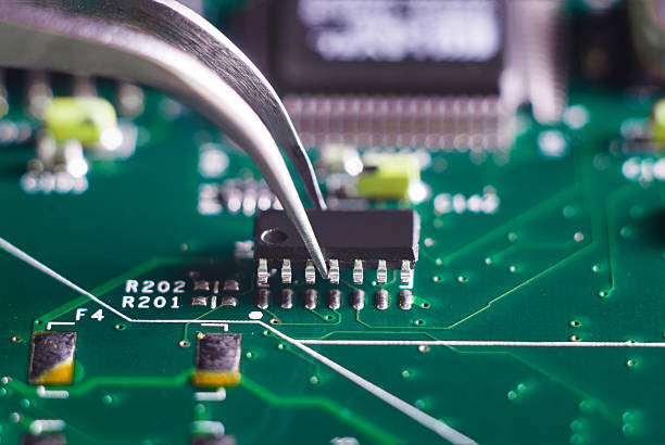 istock Close up on tweezers holding chip on computer circuit board 584600558