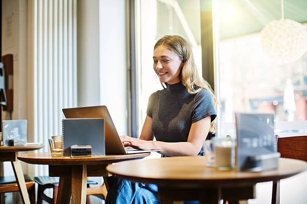 istock Smiling woman using laptop at coffee shop 584601076