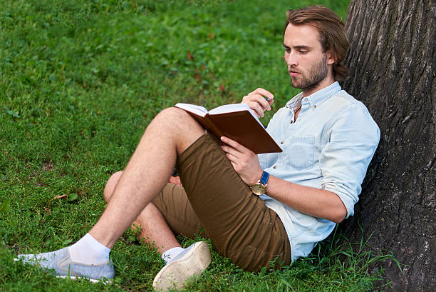 istock Serious student in park of campus read a book 584602976