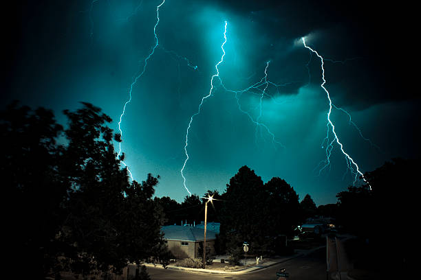 Multiple lightning bolts with cerebral abstract style behind a lit house in the foreground.