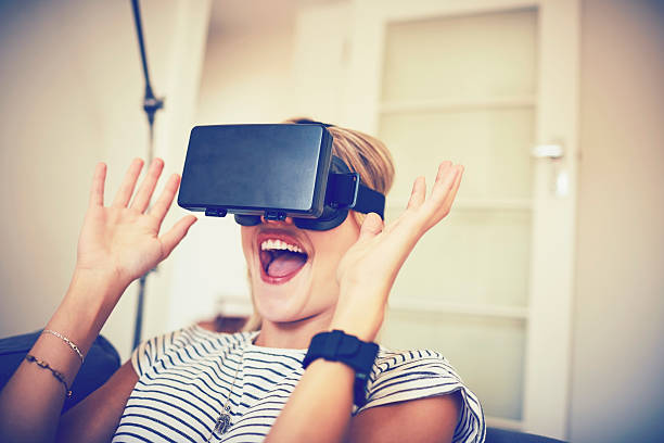 istock Excited woman using virtual reality headset at home 584743632