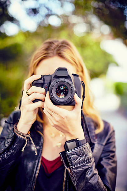 istock Young woman adjusting camera lens while taking picture on street 584744800