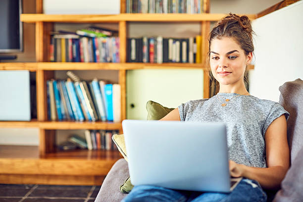 istock Beautiful young woman using laptop on sofa at home 584745032
