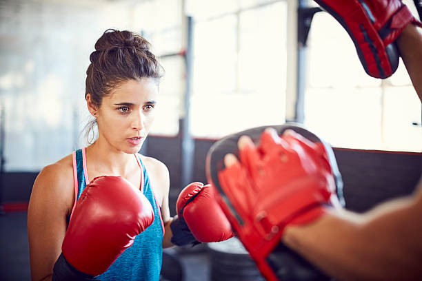 istock Young female fit boxer practicing with coach in gym 584745208