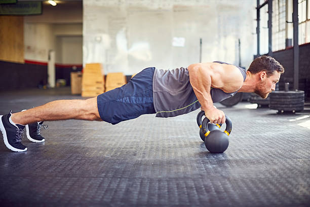 istock Focused fit man doing push-ups on kettlebells in gym 584745652