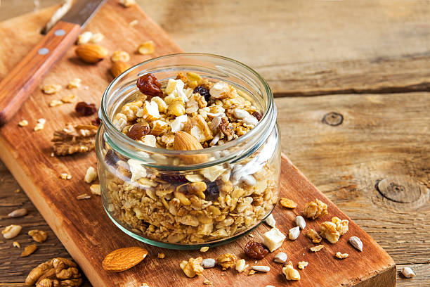 Homemade granola with nuts Homemade granola with nuts and seeds in glass jar for healthy breakfast granola photos stock pictures, royalty-free photos & images