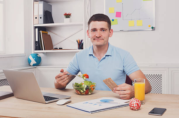istock Man has healthy business lunch in modern office interior 584747824