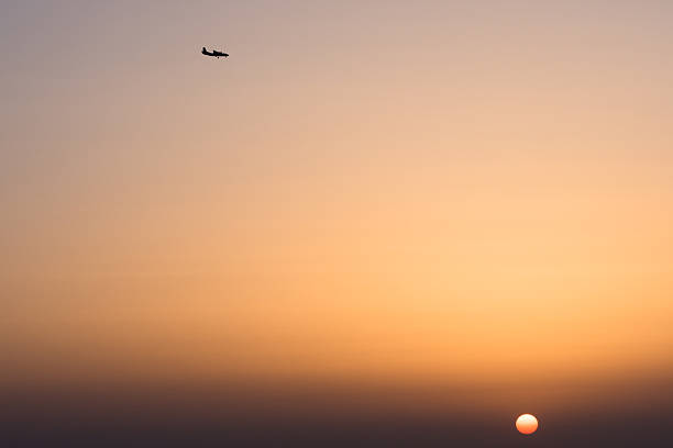 istock plane flying high in the sky above the setting sun 584748368