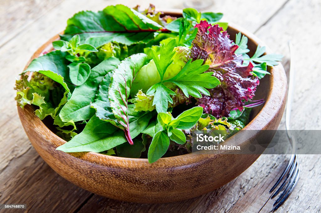 green mixed salad leaves Fresh organic green mixed salad leves over rustic wooden background close up Variation Stock Photo