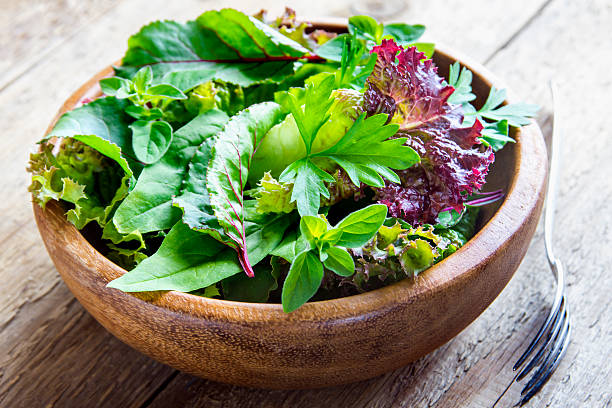 green mixed salad leaves Fresh organic green mixed salad leves over rustic wooden background close up spring mix lettuce leaves stock pictures, royalty-free photos & images