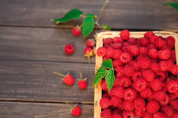 istock Red fresh raspberries basket on brown rustic wood background 584749638