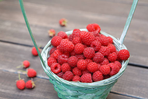 istock Red fresh raspberries basket on brown rustic wood background 584749790