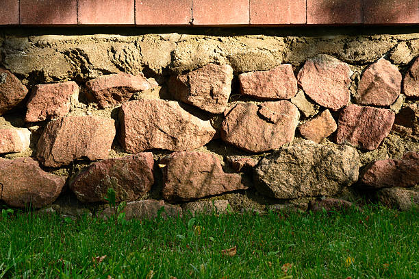 istock Brick and stone wall closeup with green weed below 584751230