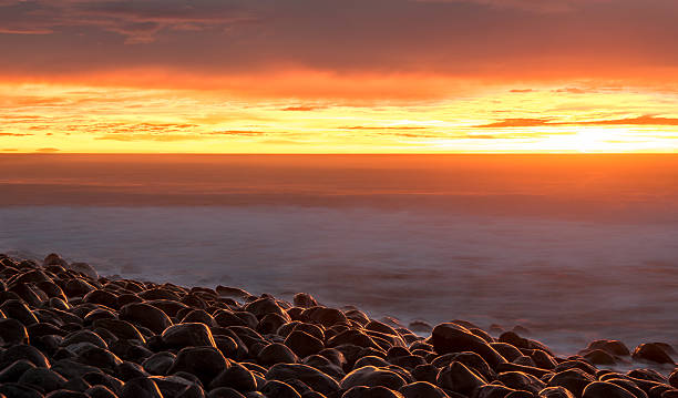 sonnenaufgang am kiesstrand. kaikoura, neuseeland - marlborough region sunrise new zealand sea stock-fotos und bilder