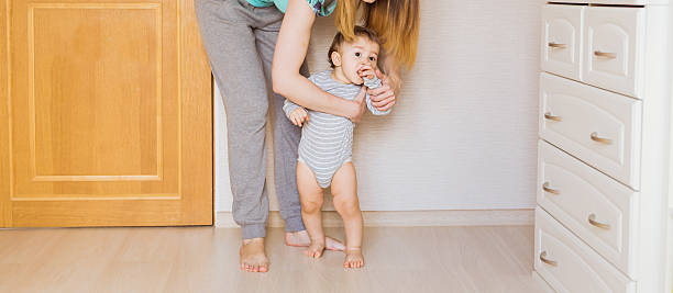 istock little boy first steps with the help of mother 584754742