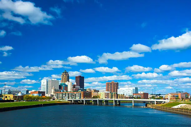 Downtown Des Moines skyline and Martin Luther King Jr. Parkway bridge, with a sea of puffy clouds in the background and the Des Moines River in the foreground.