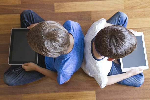 istock Children with tablets PC sitting on wooden floor at home 584760944