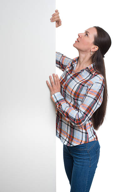 istock Beautiful brunette woman holding a blank billboard 584764344