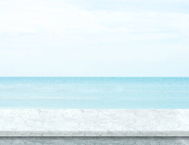 istock White marble table top with blurred sea and blue sky 584769162