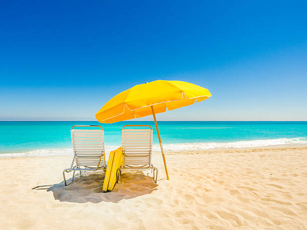 Beach chairs in South Beach Yellow beach umbrella and deck chairs on the beach on a clear day on South beach, Miami sunshade stock pictures, royalty-free photos & images