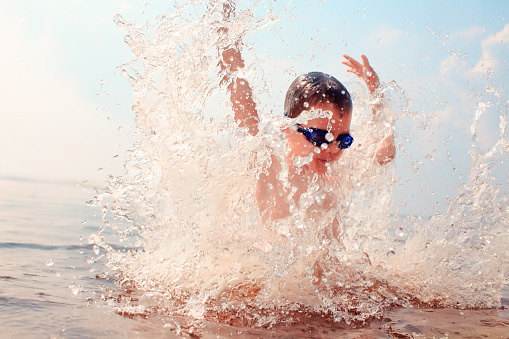 splashes of water around a swimmer diving into the water. kid excited about swimming. the concept of a happy childhood
