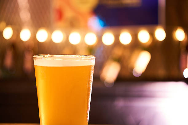 Glass of light beer on a dark pub table