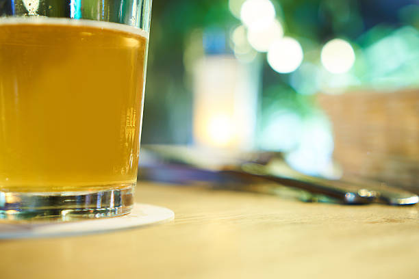 istock Glass of light beer on a dark pub table 584772882