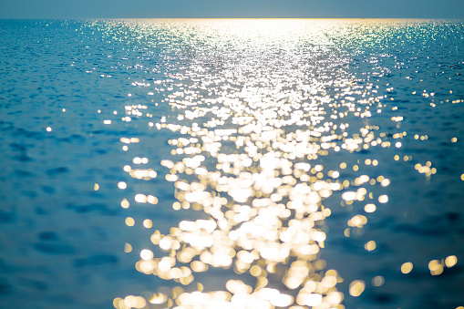 water horizon filled with light of the setting sun. blur reflection on the sea, golden sunlight