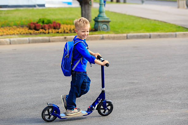 istock little boy riding scooter in the city 584777218