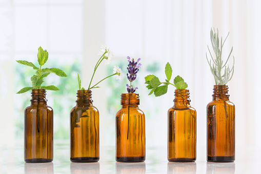 Bottle of essential oil with herbs and spices in brown bottles