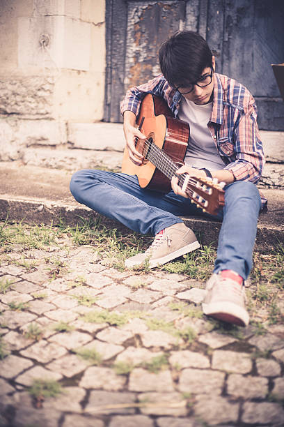 istock Handsome man is playing on guitar sitting on the road 584781380
