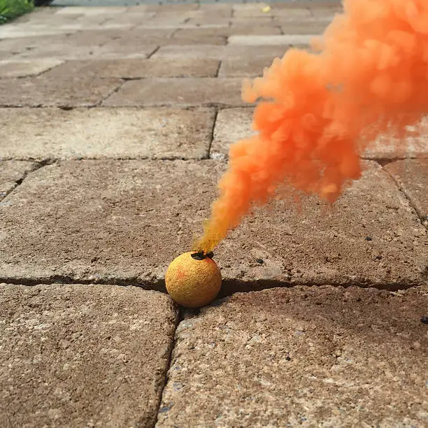Photo of Orange Smoke Bomb Fireworks on Sidewalk