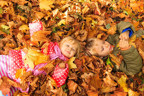 istock happy kids having fun in autumn fall leaves 584782432