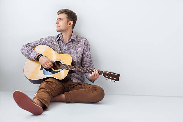 istock Portrait of handsome man playing guitar siting on floor 584782664