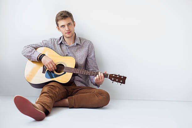istock Portrait of handsome man playing guitar siting on floor 584783928