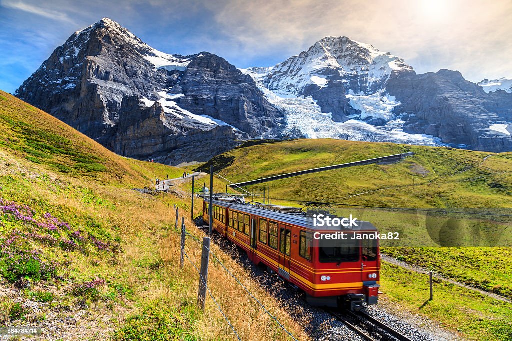 Electric tourist train and Eiger North face,Bernese Oberland,Switzerland Famous electric red tourist train coming down from the Jungfraujoch station(top of Europe) in Kleine Scheidegg,Bernese Oberland,Switzerland,Europe Train - Vehicle Stock Photo