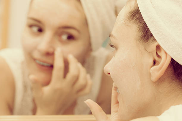 istock Woman applying mask cream on face in bathroom 584785292
