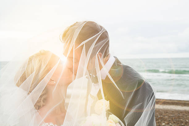 Wedding Just married: Wedding picture of young, beautiful couple standing on beach, Denmark veil photos stock pictures, royalty-free photos & images