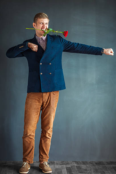 istock Handsome young man dancing with a red rose in mouth 584788580