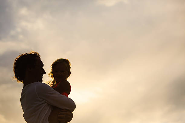 istock Father and little daughter silhouettes at sunset 584789094